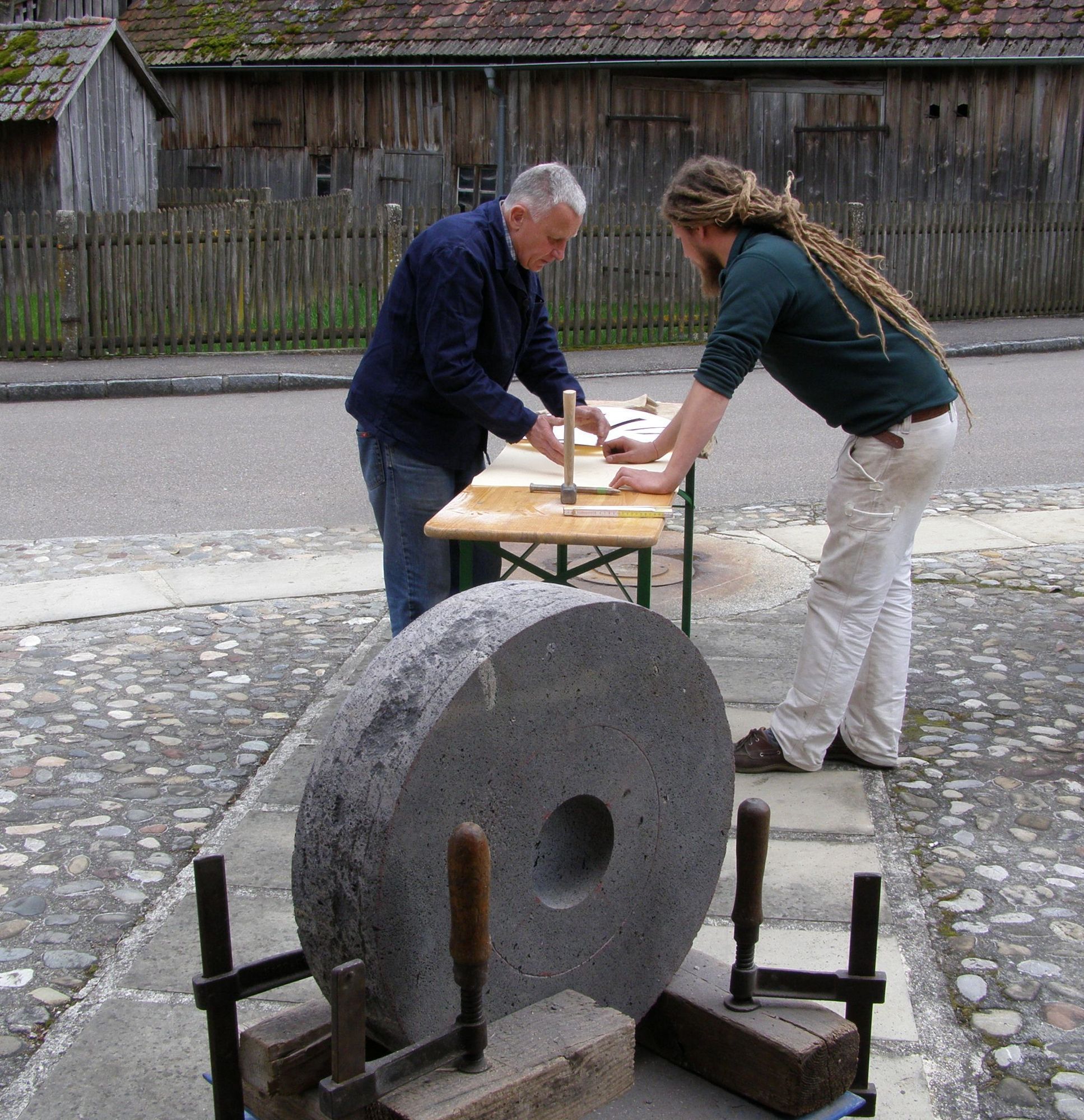 Wolfgang Strakosch (links) pflegt noch das alte Handwerk des Steineschärfens, das er André Rösner (rechts) zeigt, Foto: LRA