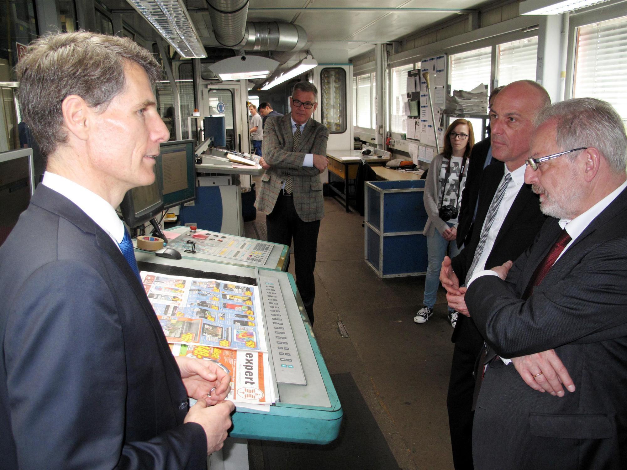 Verleger Thomas Sixta mit seinen Gästen vor einer Druckmaschine. Foto: Landratsamt Aichach-Friedberg