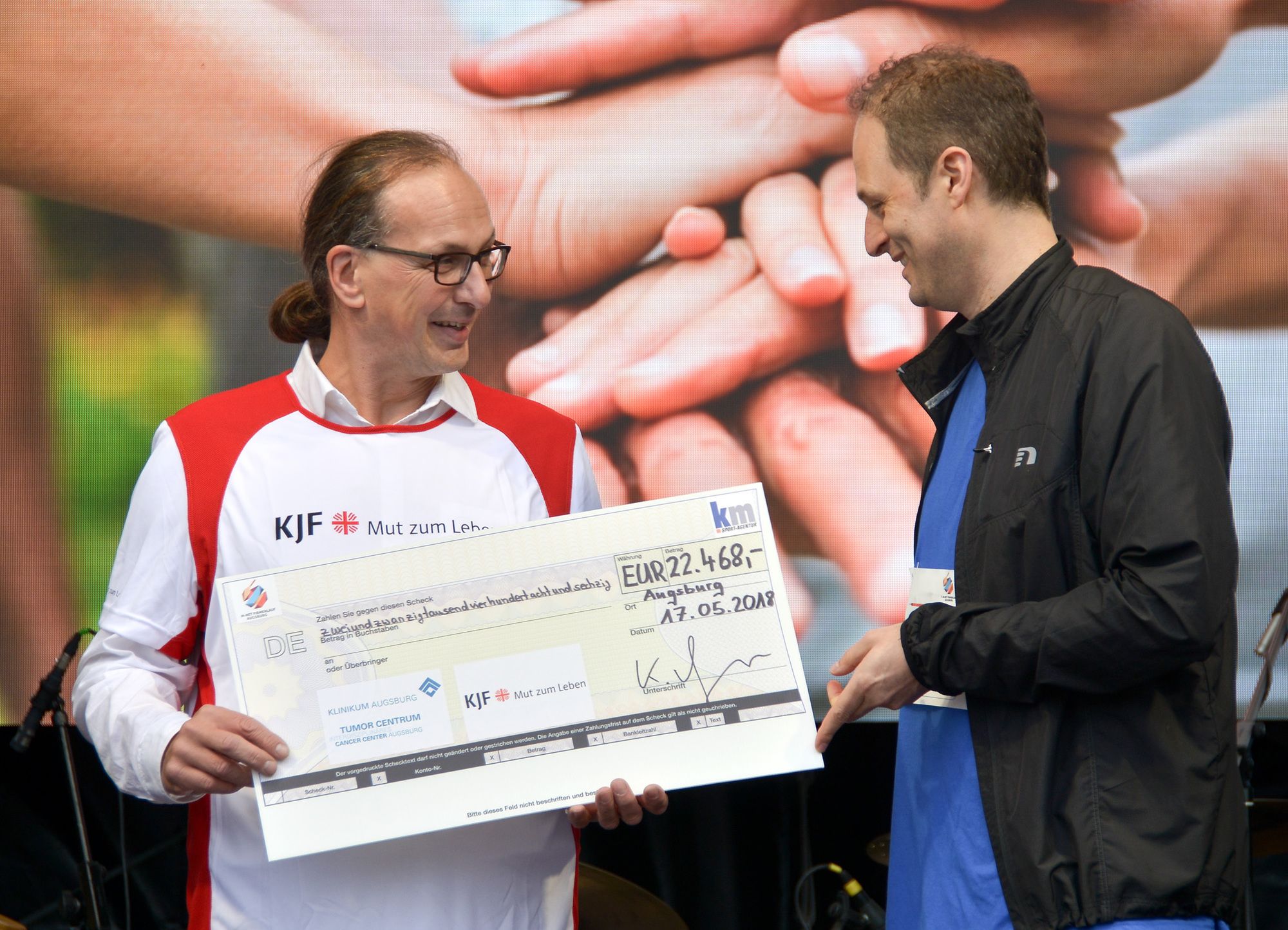Prof. Dr. Thomas Kröncke (rechts) nimmt den symbolischen Scheck entgegen. Foto: Klinikum Augsburg