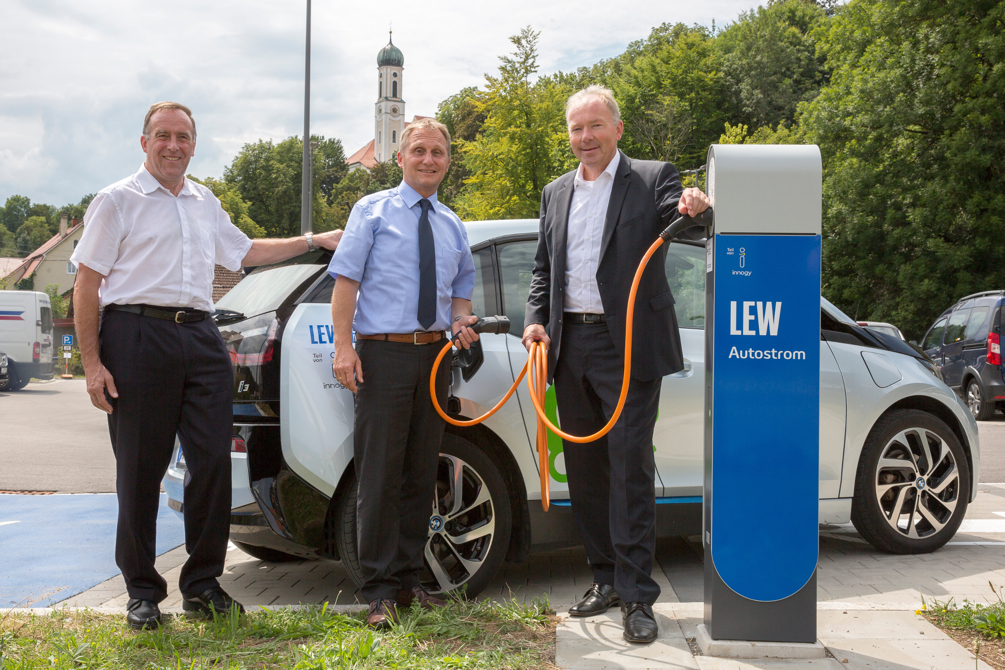 Peter Kraus, Falk Sluyterman van Langeweyde und Norbert Schürmann nehmen die Wechselstrom-Ladestation am Parkplatz im Buchenweg in Betrieb. Foto: LEW / Julian Leitenstorfer