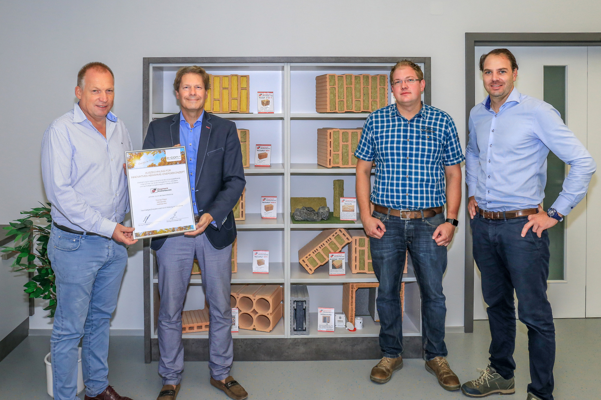 Andreas Müller (links) überreicht Thomas Thater die Urkunde für das innovative Abwärme-Energiekonzept im Beisein von Michael Offner und Michael Hörl (rechts). Foto: Ziegelwerk Klosterbeuren