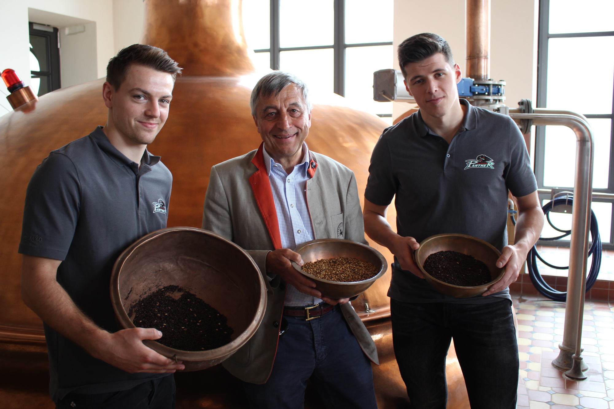 Die Panther-Profis Jakob Mayenschein (links) und Alex Lambacher beim traditionellen Panther-Pur Einbrauen mit Riegele-Chef Sebastian Priller. Foto: Angelina Märkl/B4B WIRTSCHAFTSLEBEN SCHWABEN