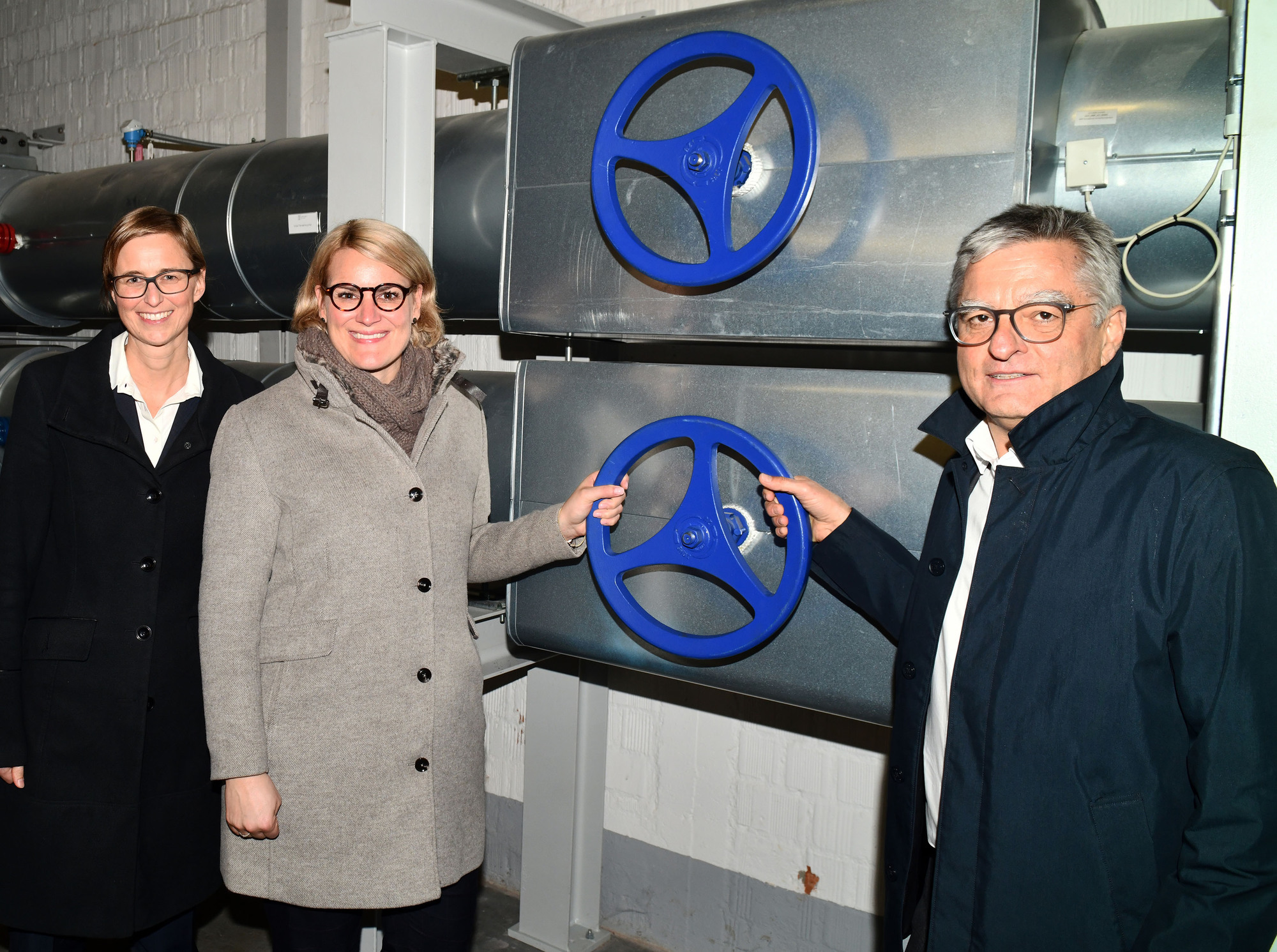 Hier fließt die grüne Wärme ins Gebäude. Von links: Antje Schmid, Leiterin Facility Management KUKA, Bürgermeisterin Eva Weber und swa-Geschäftsführer Alfred Müllner öffnen symbolisch die Schleusen. Foto: swa / Thomas Hosemann