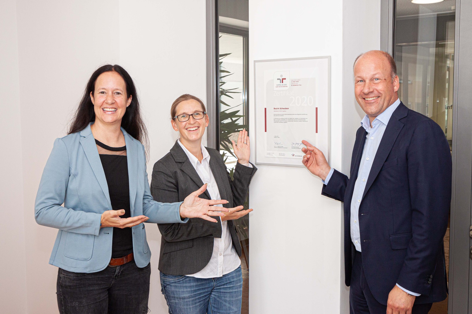 Gleichstellungsbeauftragte Nadja Hein, Birgit Zeitz von der Personalverwaltung und Bezirkstagspräsident Martin Sailer freuen sich über das Zertifikat von audit berufundfamilie im Hauptgebäude des Bezirks Schwaben in Augsburg. Foto: Daniel Beiter / Bezirk Schwaben