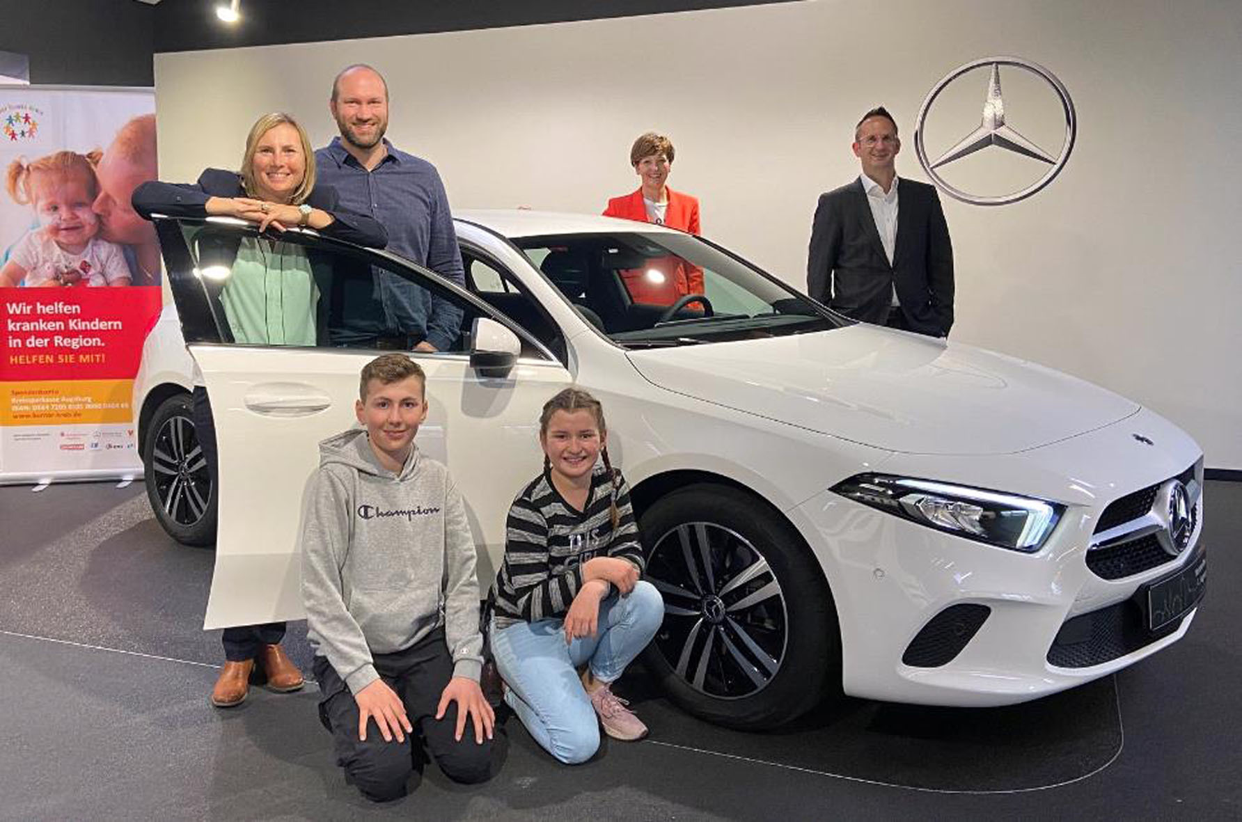 Der Hauptpreis der Dankeschön-Verlosung des Bunten Kreises, geht an Sandra Eberhardt-Remmele aus Meitingen. Mit ihr und ihrer Familie freuen sich Steffen Schwenkglenks, Leiter der Mercedes-Benz Niederlassung Augsburg PKW (rechts) und Astrid Grotz, Vorstand der Stiftung Bunter Kreis (in der Bildmitte). Foto: Bunter Kreis