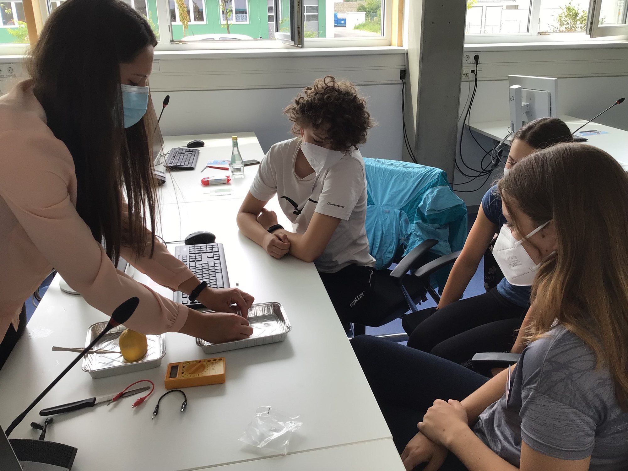 Eva Enslin (Varta AG Group) zeigt den Teilnehmerinnen Ronja, Lena und Luzia ein Experiment. Foto: Viktoria Kotzschmar