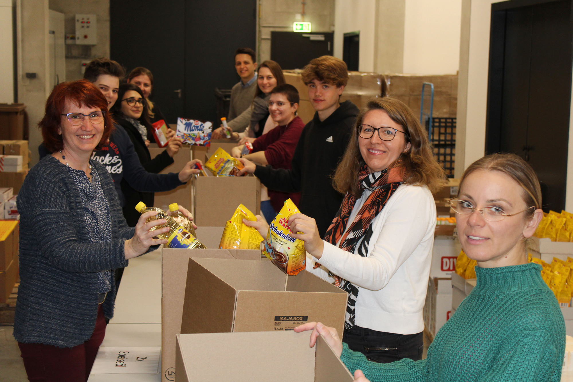 Das Team der Molkerei Zott packt Weihnachts-Pakete für den Weihnachtstruck der Johanniter.