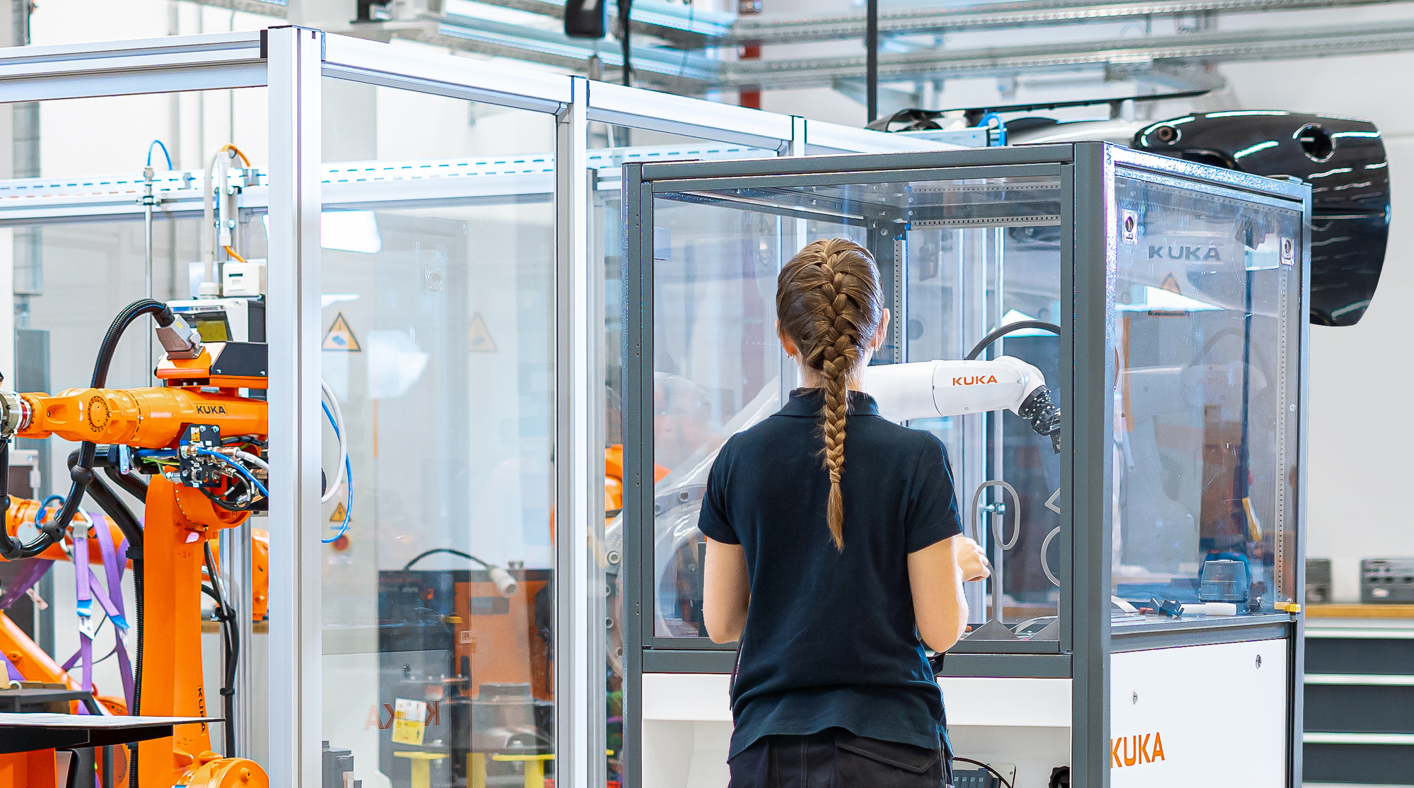 Eine angehende Kukanerin vor einem Roboter. Foto: Kuka