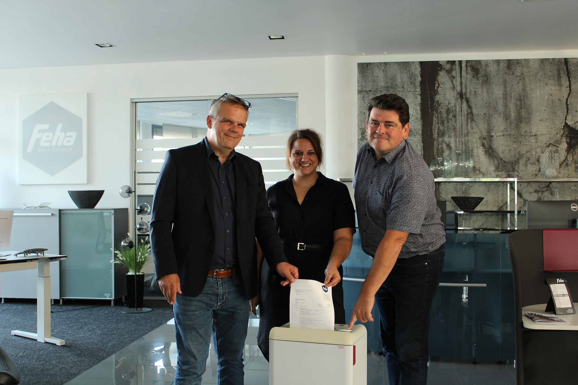 Feha verzichtet auf Rechnung: Mathias Abel, Saskia Fehn und Alfred Schmalberger (v.l.n.r.) schreddern symbolisch die Rechnung an die Caritas Günzburg. Foto: Jasmina Spiegler / Feha Büro-Technik