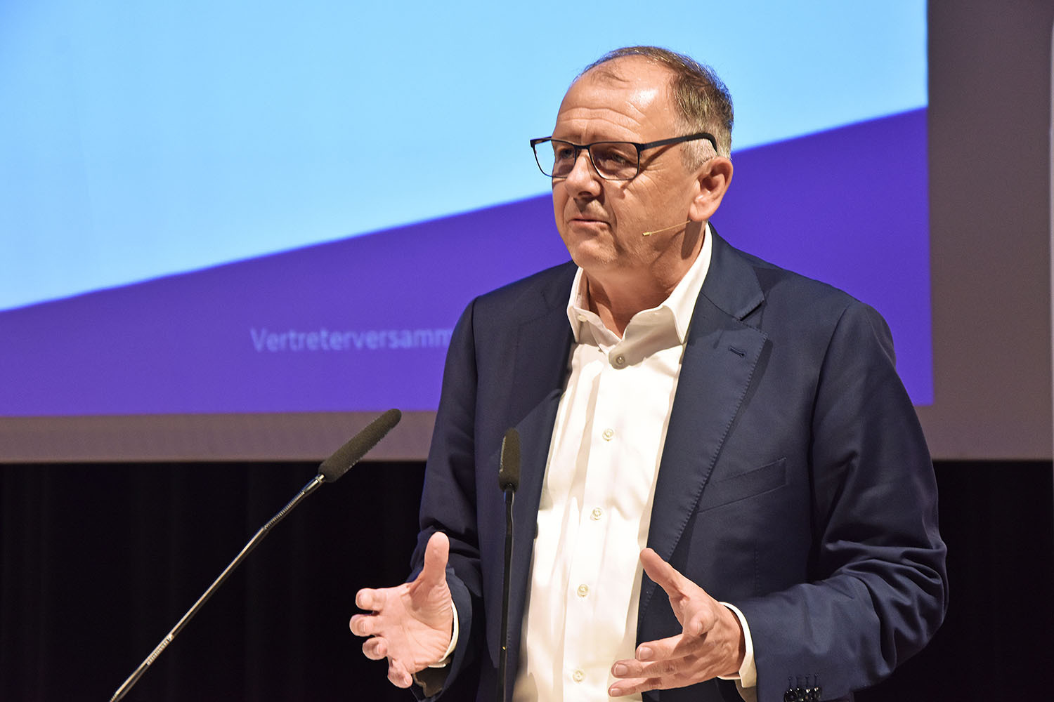 Georg Schneider, Vorstandsvorsitzender der VR Bank Handels- und Gewerbebank vor einem Podium mit Mikrofon.