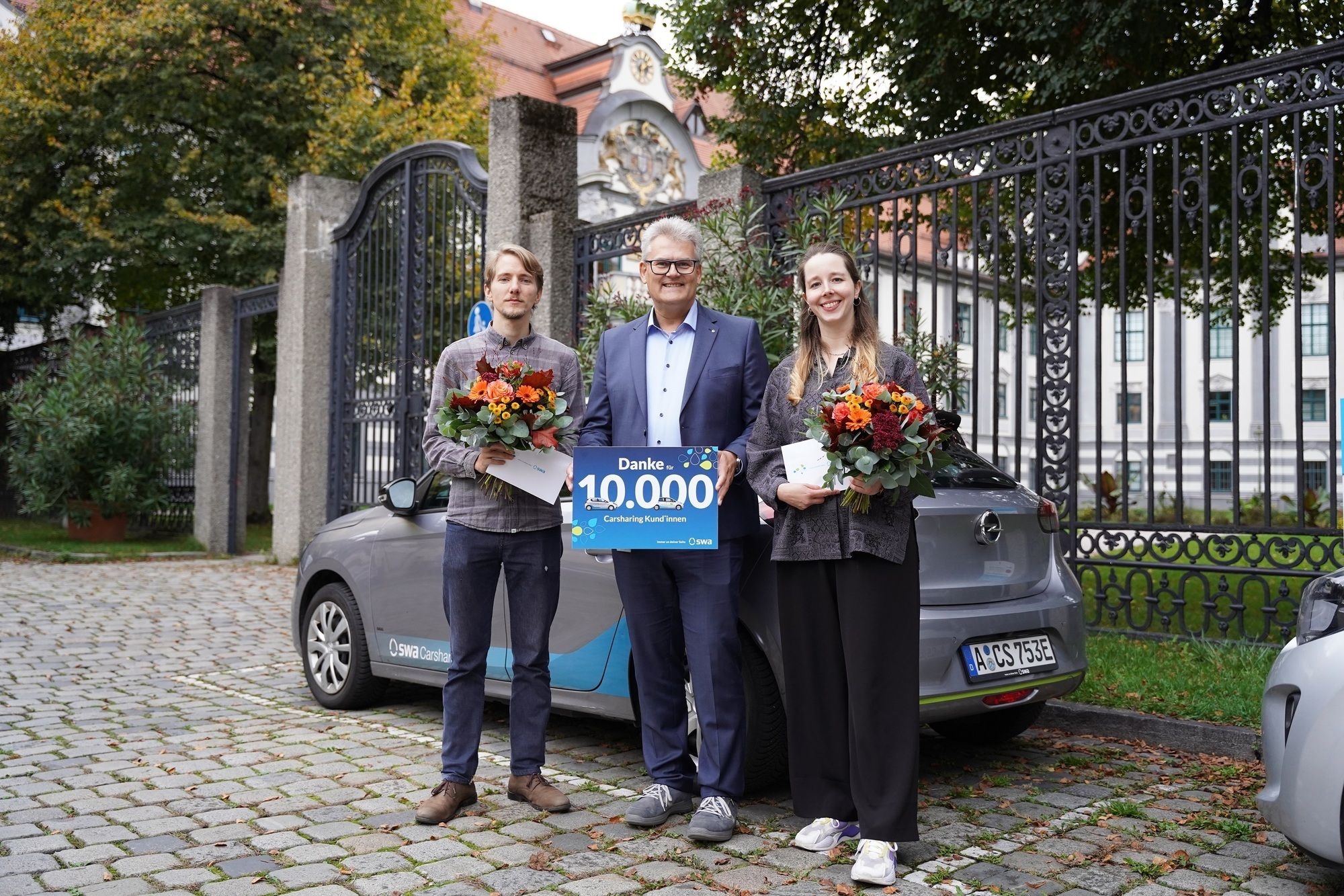 Einer der treuesten Carsharing-Kunden Moritz und die 10.000 swa Carsharing-Kundin Magdalena freuen sich über ein kleines Dankeschön, übergeben von swa Geschäftsführer Rainer Nauerz (Bildmitte). Foto: swa / Diyar Bozoglu