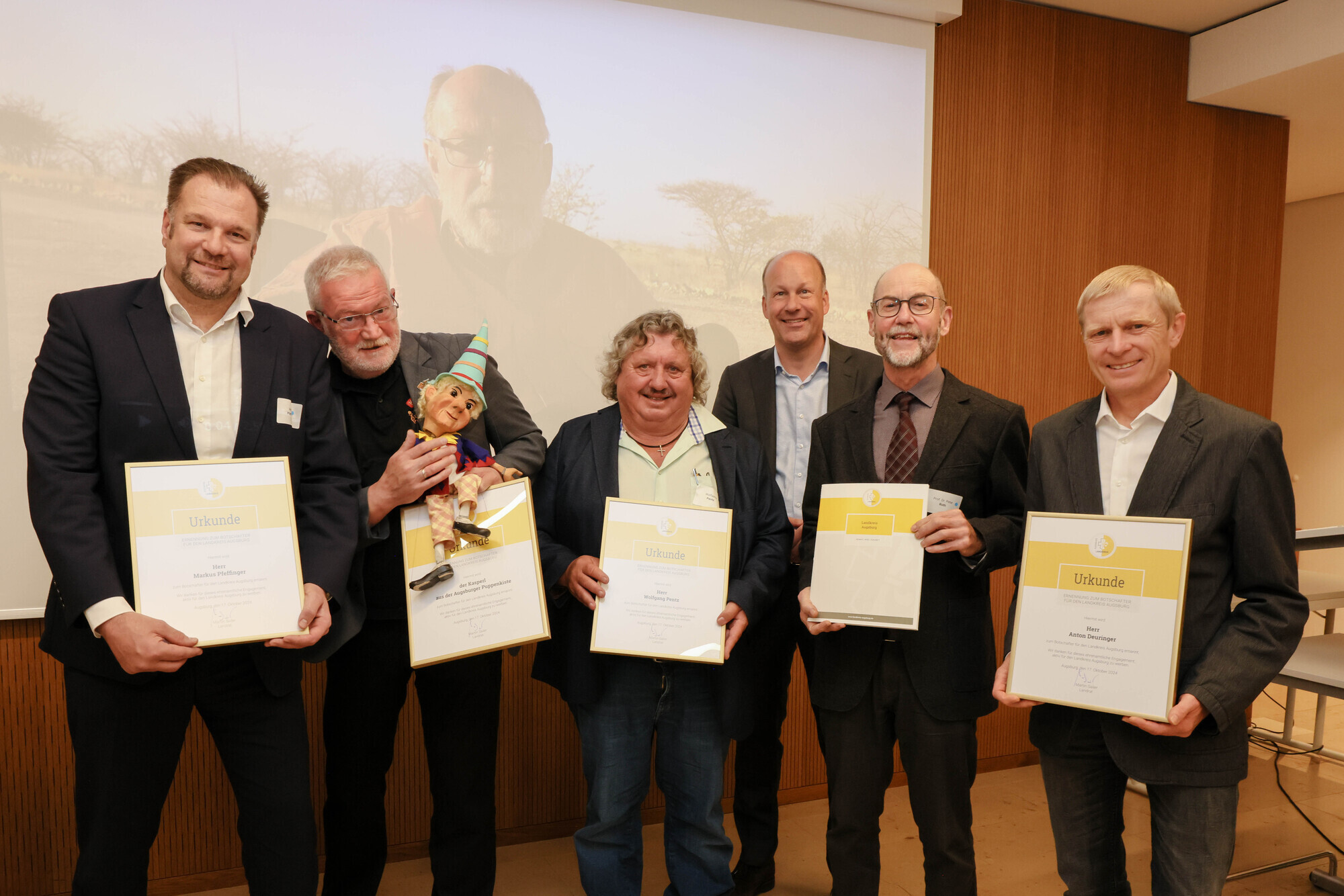 (v. l. n. r.) Markus Pfeffinger, Klaus Marschall mit dem Kasperl, Wolfgang Petz, Landrat Martin Sailer, Prof. Dr. Peter Roth und Anton Deuringer. Auf der Leinwand im Hintergrund Horst Erhardt. Foto: Julia Pietsch