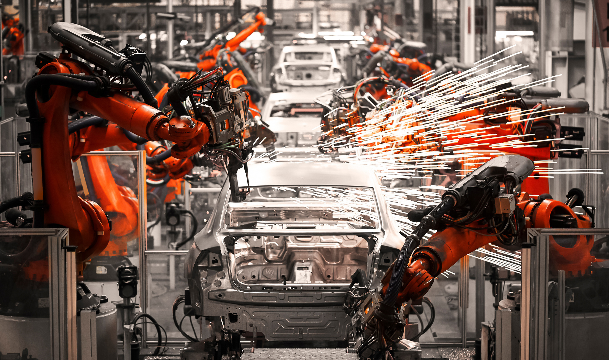 Silberne Autokarosserien werden hintereinander von Roboterarmen bearbeitet. Automobilzulieferer rutschen auch in die Krise.