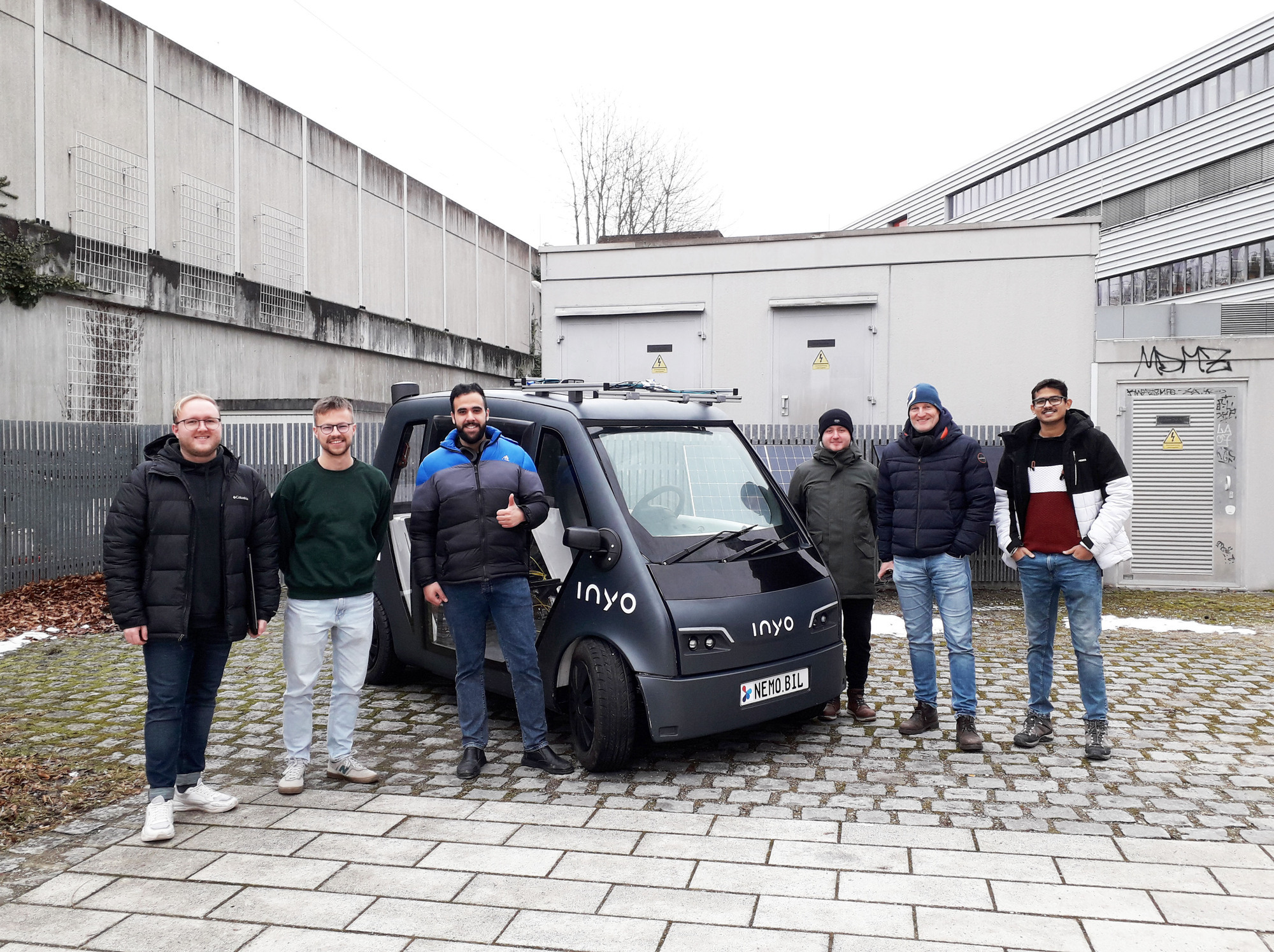 Prof. Dr.-Ing. Carsten Markgraf (2. v. r.) zusammen mit seinem Team an wissenschaftlichen Mitarbeitern und einem NeMo.bil-Fahrze
