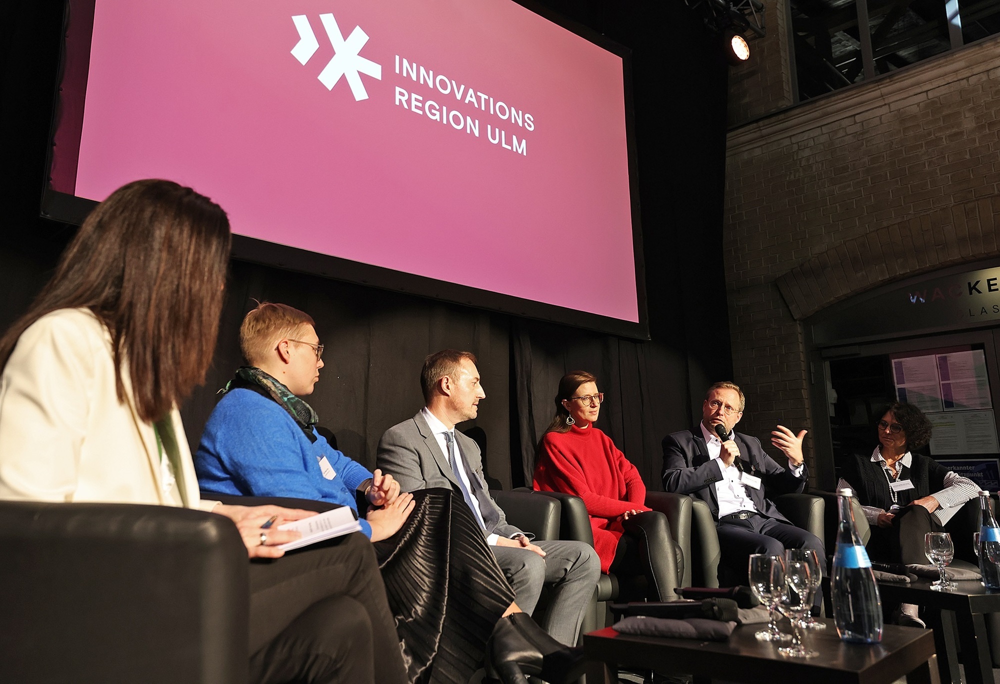 Panel zur politischen Lage Deutschlands und den konkreten Herausforderungen und Perspektiven der Innovationsregion Ulm.V. l. n. r. Chrissie Weiss (Moderatorin), Eva Treu (Landrätin des Landkreises Neu-Ulm und Vorstandsvorsitzende der Innovationsregion Ulm), Markus Möller, (Erster Landesbeamter und stellvertretender Landrat des Alb-Donau-Kreises), Katrin Albsteiger (Oberbürgermeisterin der Stadt Neu-Ulm, Martin Ansbacher (Oberbürgermeister der Stadt Ulm) und Petra Engstler-Karrasch (Hauptgeschäftsführerin der IHK Ulm). Foto: Innovationsregion Ulm/Armin Buhl