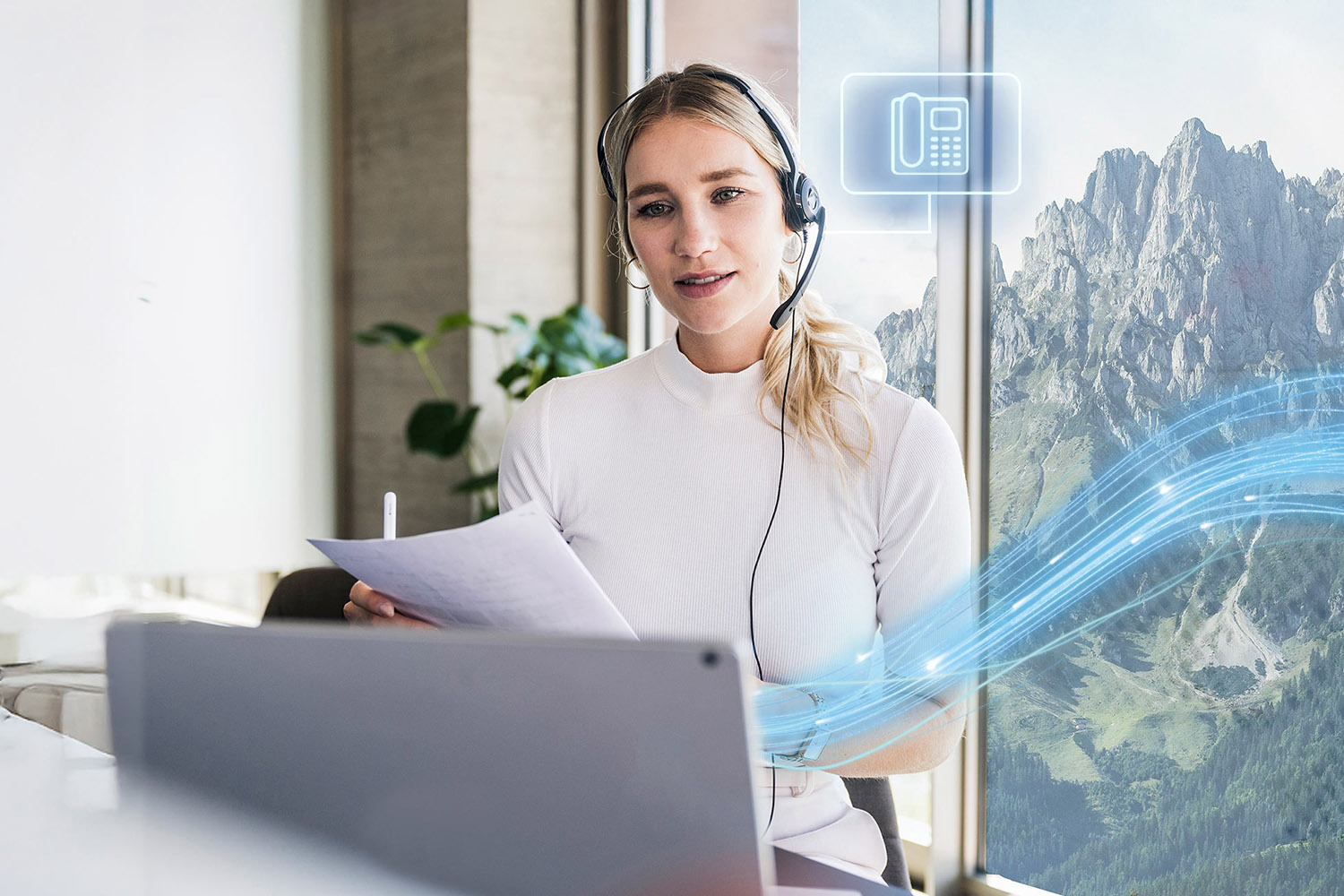 Eine Frau trägt ein Headset und arbeitet an ihrem Laptop