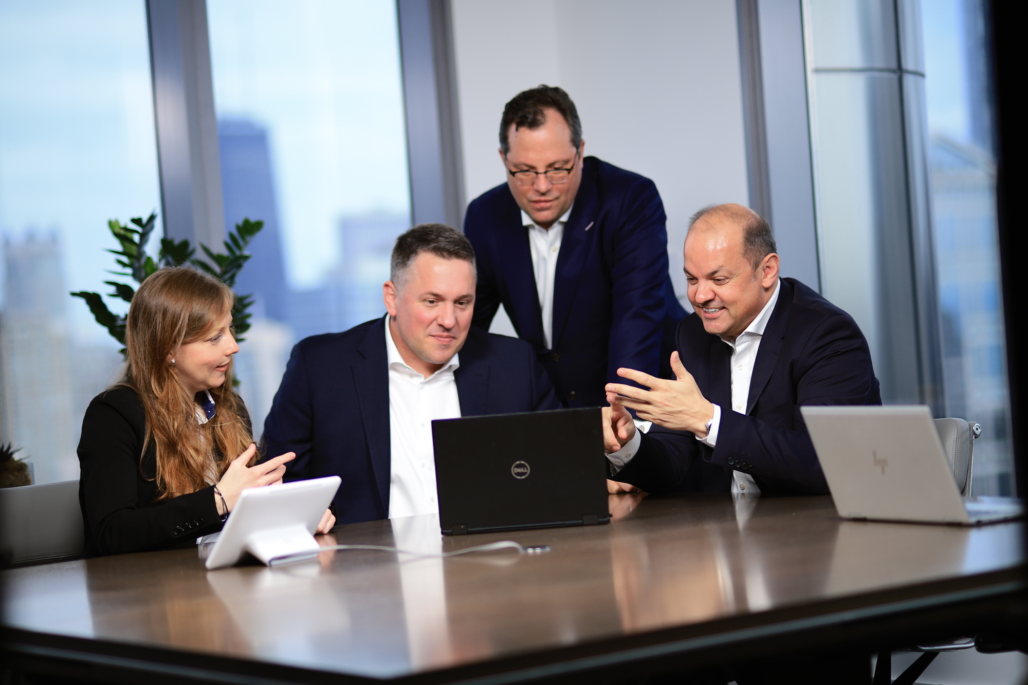 Vier Experten von US Business Partners sitzen vor einem Laptop und besprechen ihr Tagesgeschäft