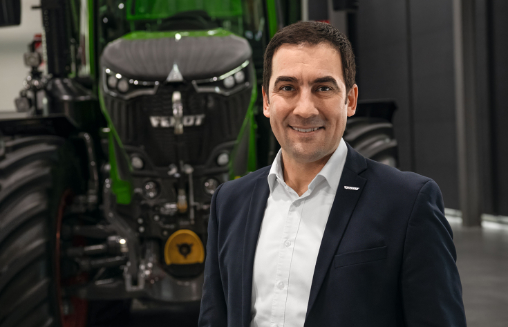 Dr. Josef Mayer steht in einem legeren Anzug vor einem Fendt-Traktor