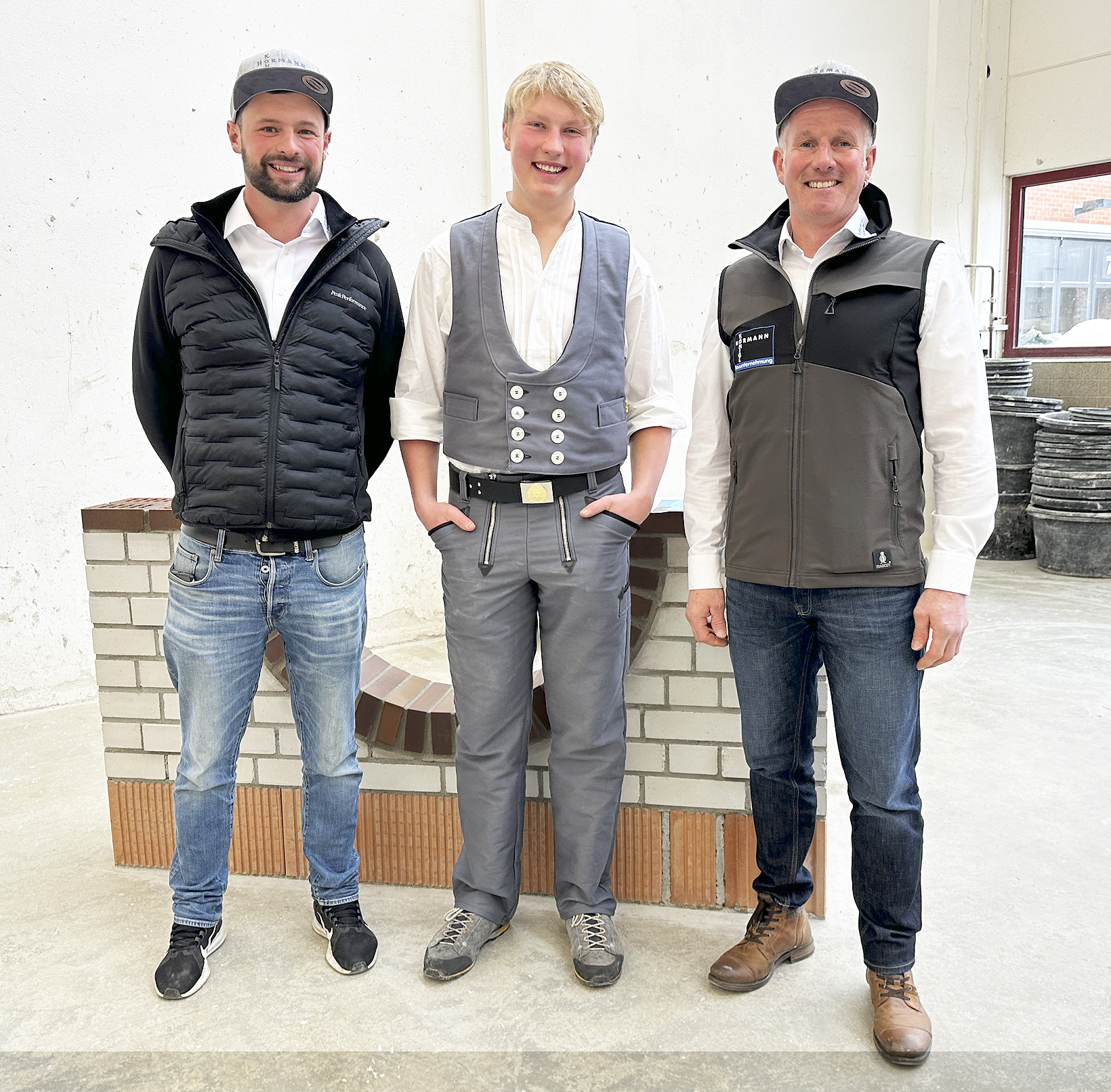 Das Foto zeigt Andreas Kiechle (Mitte) vor seinem Prüfungsmauerwerk mit Peter Hörmann (rechts), Geschäftsführer von Königl und H