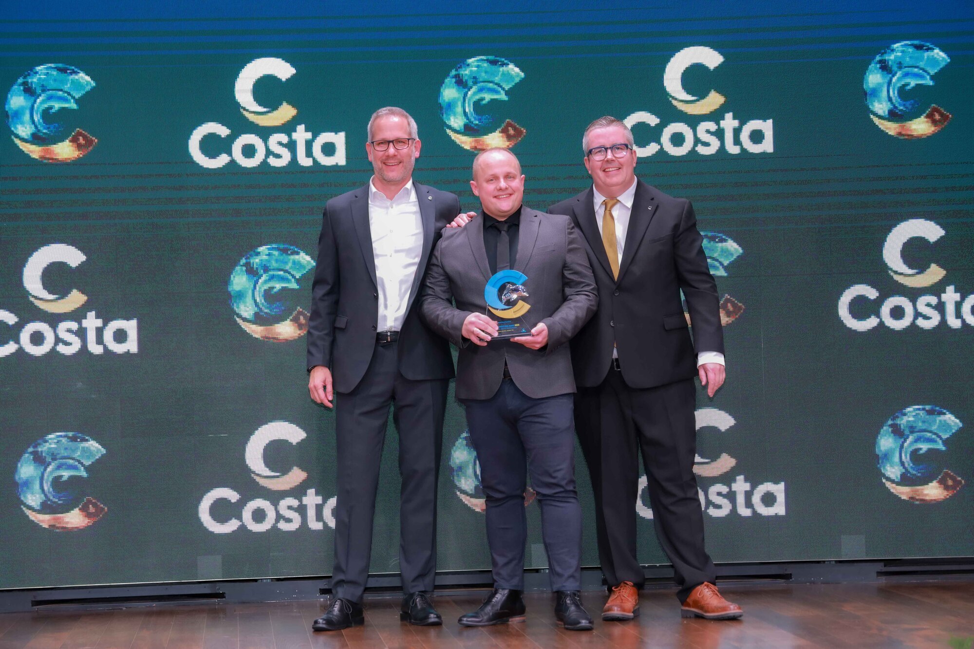 Florian Liebl (Hörmann Reisen) nimmt von Olaf Kistenmacher (li., Costa Sales Director Germany) und Achim Etzl (re., Key Account