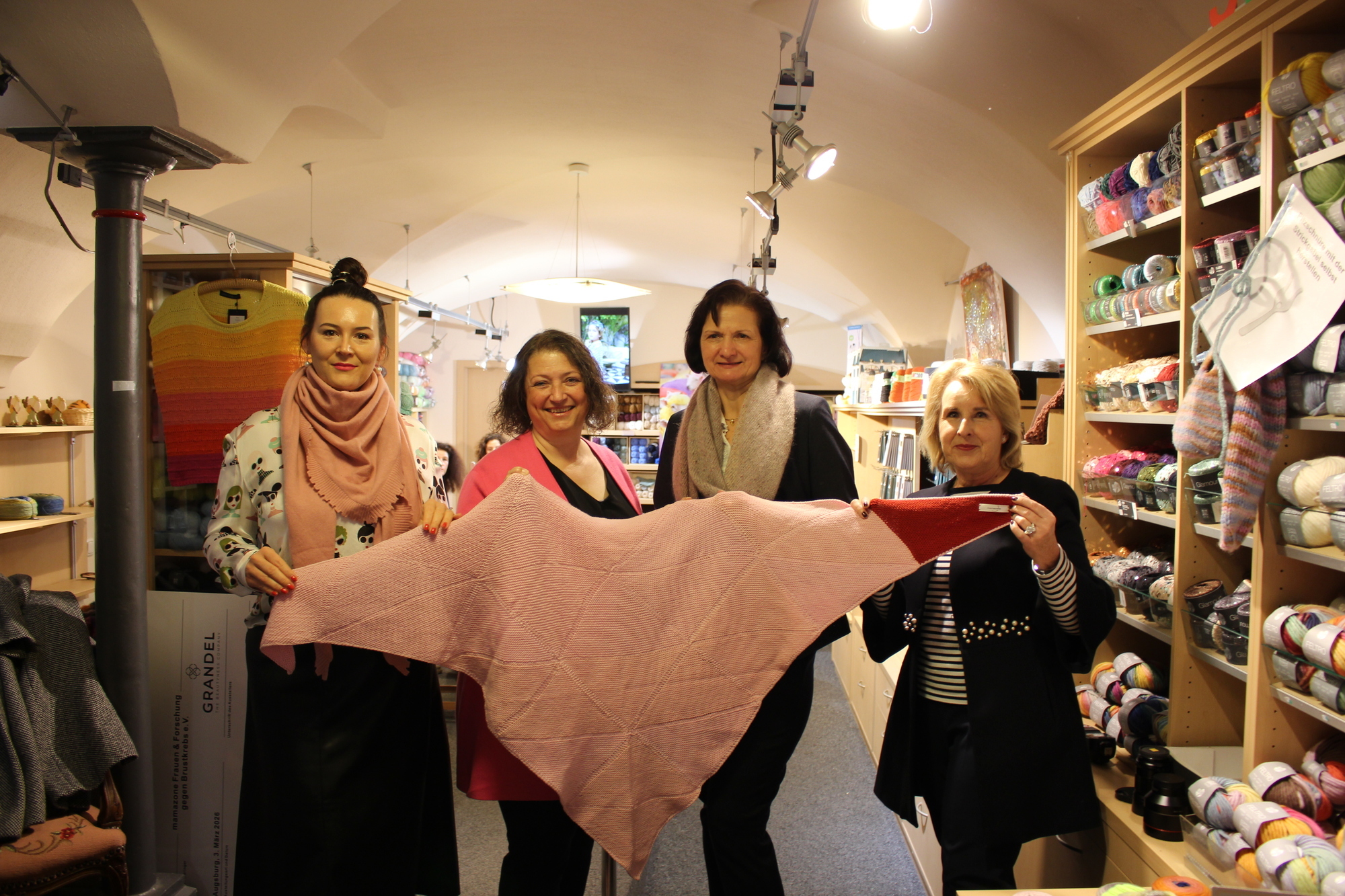Das Umarmungstuch für Brustkrebspatientinnen. Dafür engagieren sich Ariane Grandel (l.), Biggi Welter (2. v. l.), Renate Abstreiter (2. v. r.), Filialleiterin von Woll-Schaefer in Augsburg, und Christine Schwarzer (r.), ehemalige Mitarbeiterin bei Grandel. Foto: B4B/ Katharina Seeburger