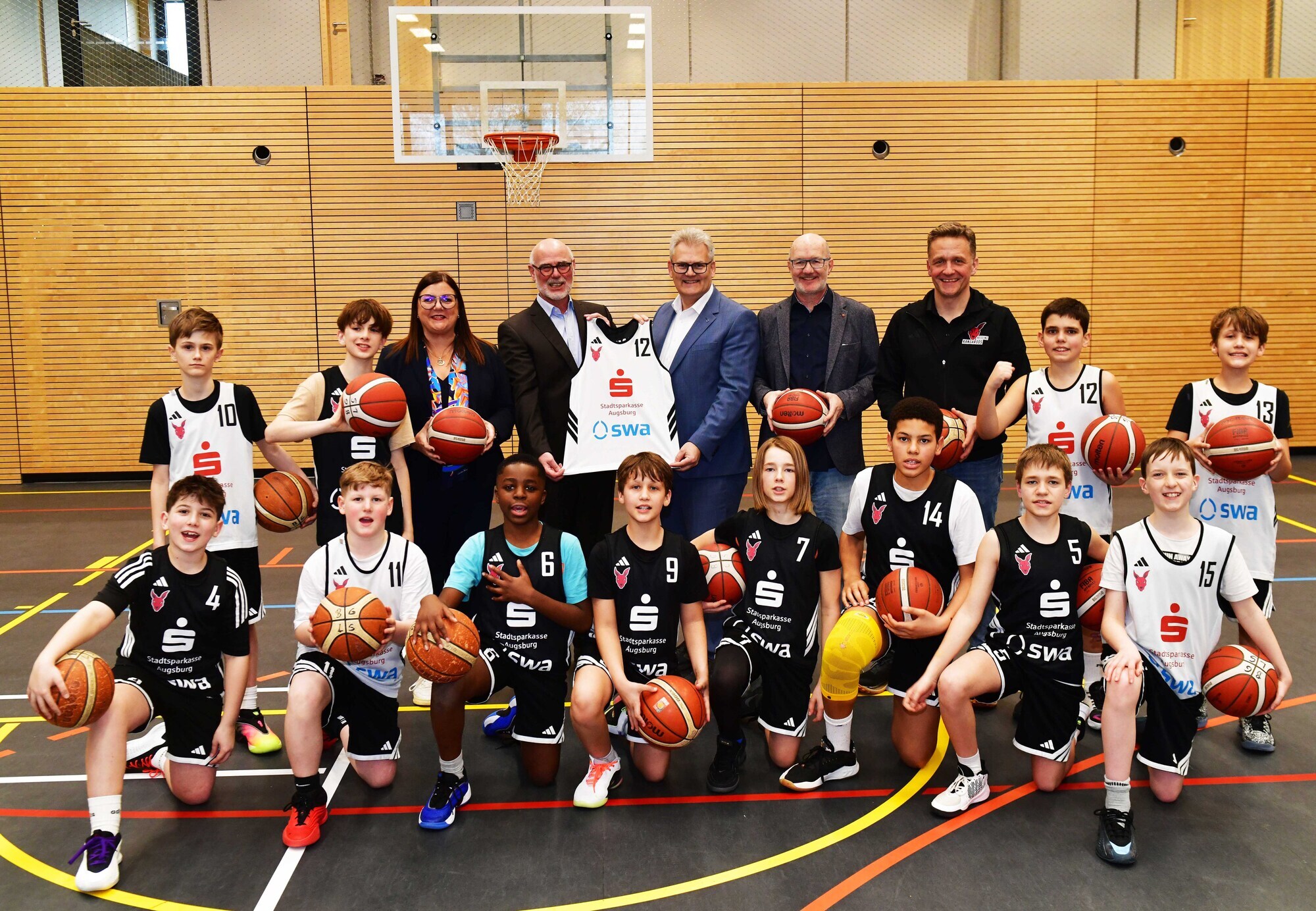 Umgeben von den Spielern der U12 der TSG Stadtbergen sind auf dem Bild zu sehen (v.l.n.r.): Sandra Peetz-Rauch (Vorstandsvorsitzende der Stadtsparkasse Augsburg), Uwe Hartung (2. Vorstand TSG Stadtbergen), Rainer Nauerz (Geschäftsführer der Stadtwerke Augsburg), Hans Kiesling (Abteilungsleiter Basketball der TSG Stadtbergen) und Stefan Goschenhofer (Sportlicher Leiter Nachwuchs TSG Stadtbergen). Foto: swa/Thomas Hosemann