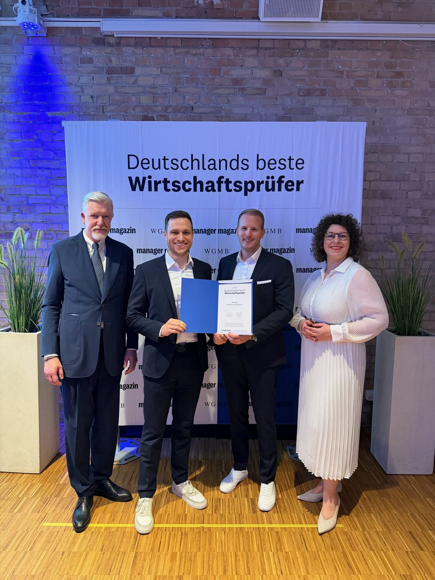 Dietmar Fink (l.), wissenschaftlicher Direktor der Wissenschaftlichen Gesellschaft für Management und Beratung, und Simone Salden, stellv. Chefredakteurin des Manager Magazins (r.) überreichen Felix Hofstetter (2. v. l.) und Dominic Wörlein (3. v. l.)  von Sonntag und Partner die Auszeichnung „Deutschlands beste Wirtschaftsprüfer 2026/27“. Foto: Sonntag