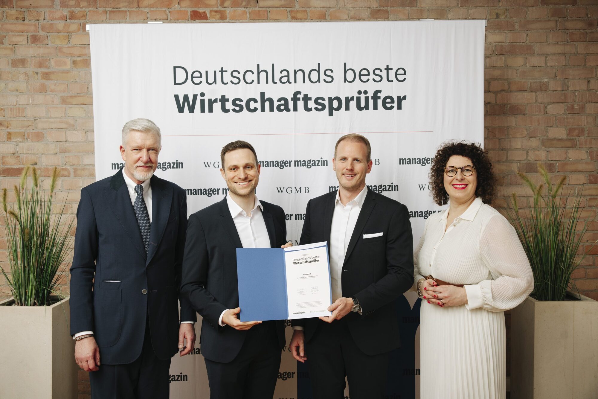 Dietmar Fink (l.), wissenschaftlicher Direktor der Wissenschaftlichen Gesellschaft für Management und Beratung, und Simone Salden, stellv. Chefredakteurin des Manager Magazins (r.) überreichen Felix Hofstetter (2. v. l.) und Dominic Wörlein (3. v. l.) von Sonntag die Auszeichnung „Deutschlands beste Wirtschaftsprüfer 2026/27“. Foto: Nói Crew / manager magazin