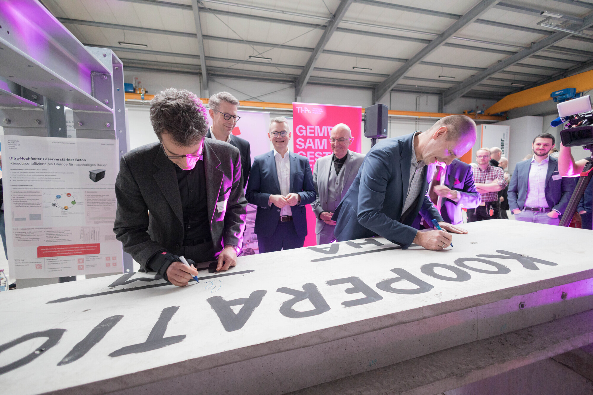 Frank Danzinger (r.), Vizepräsident für Technologie und Forschung der THA und Christian Seiler (l.), Dekan an der Fakultät Bauingenieurwesen der Hochschule München, unterzeichnen die gemeinsame Kooperationsvereinbarung – symbolisch auf einer querschnittsoptimierten Carbon-Betonplatte für Gebäude, die am TTZ Aichach entwickelt wird. Foto: Matthias Leo/THA