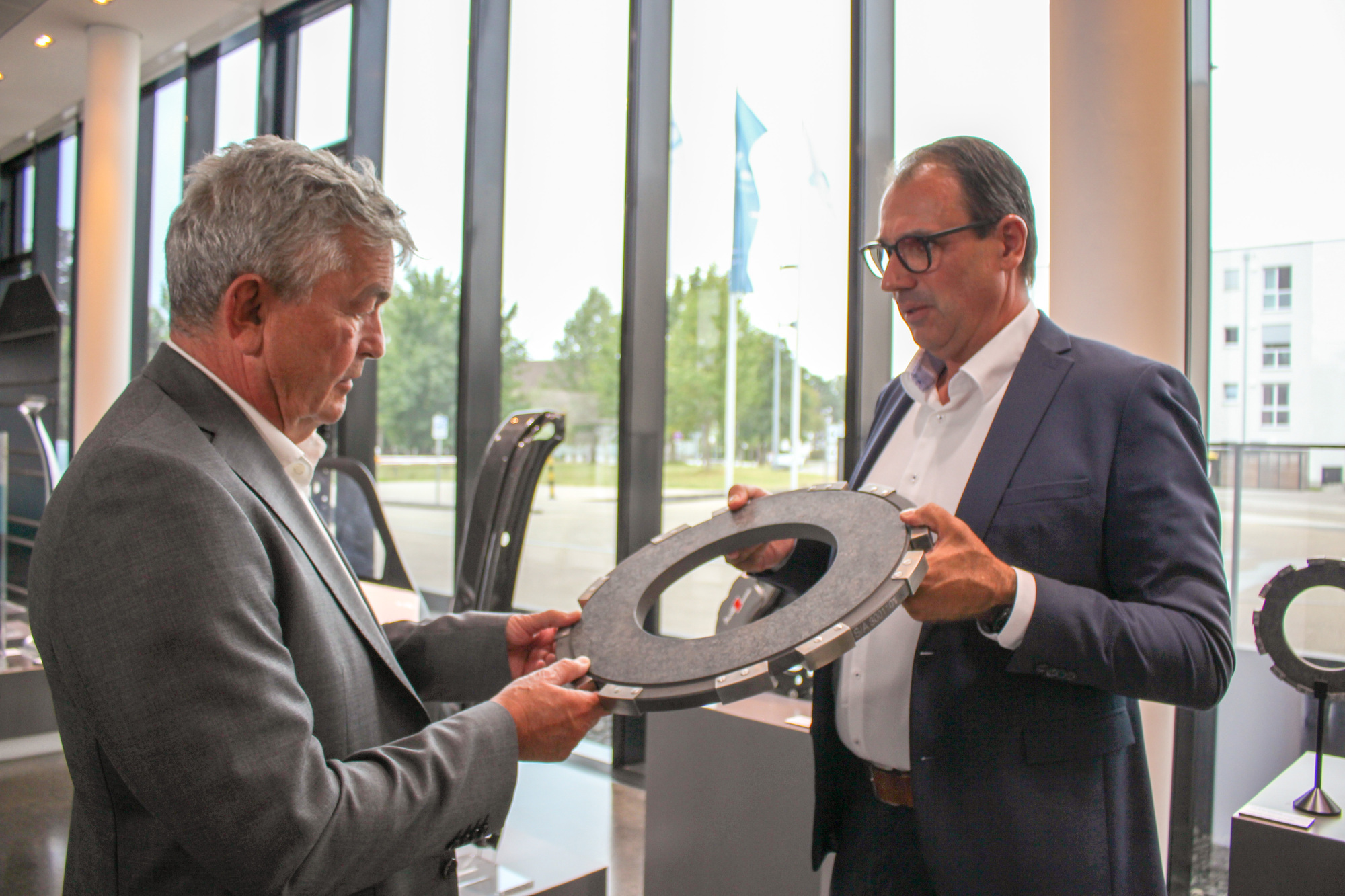 Alexander Miehling (r.) zeigt Bertram Brossardt (l.) einen Bremsrotor aus Carbonfaser für ein Passagierflugzeug. Foto: B4B/ Katharina Seeburger